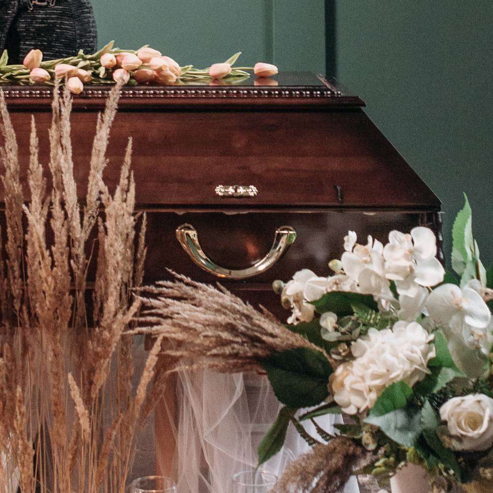 A coffin with bouquets of flowers laid over the top.